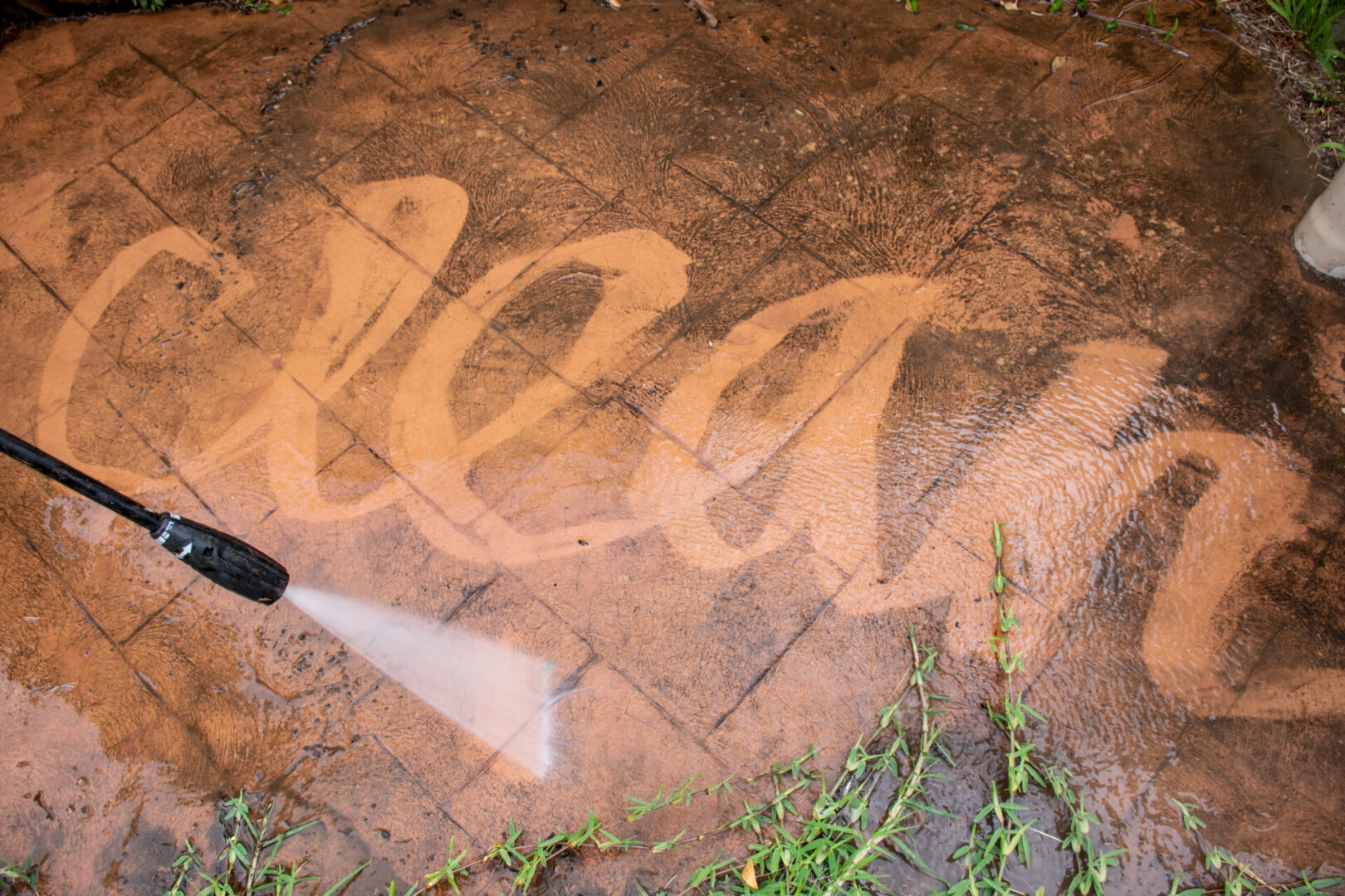 Dirty brick pavers with the word clean power washed on them.