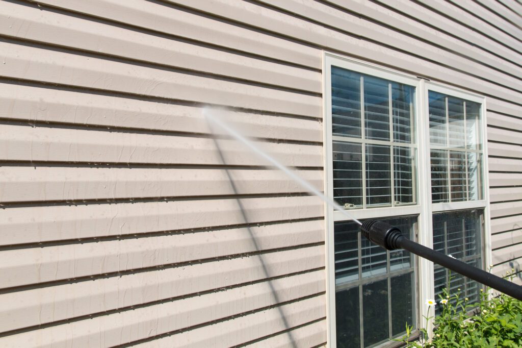 Power washing. House wall siding cleaning with high pressure wat